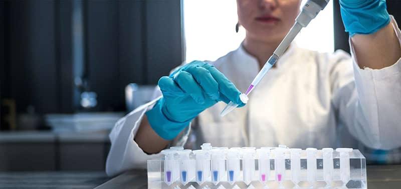 scientist pipetting colored chemicals into a tube